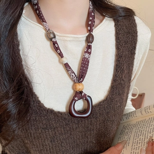 Close-up of ethnic fabric printed necklace with wooden beads and a brown resin pendant