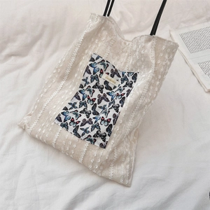 Détail du sac en toile crème avec poche papillon bleue et textures dentelle délicates