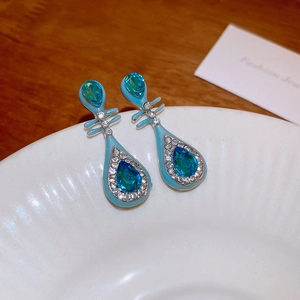 Detail of blue enamel teardrop earrings with crystals on a white ceramic plate