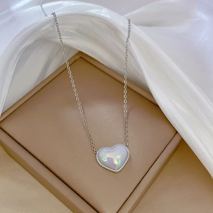 Dettaglio del ciondolo a cuore in argento con riflessi perlati su una catena sottile
