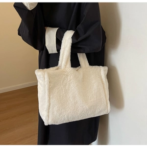 Détail du sac cabas blanc en peluche avec texture douce, tenu par un mannequin en noir