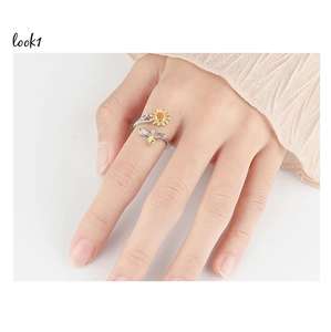 Detail shot of spinning sunflower and bee ring on model finger with golden accents