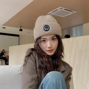 Bonnet en tricot épais avec broderie grenouille beige en laine porté par un modèle