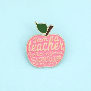 Close-up of pink apple enamel brooch with I am a teacher What is your Superpower text