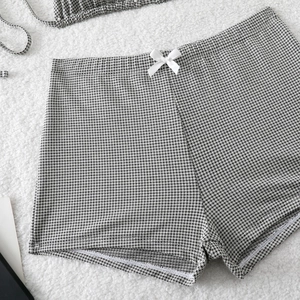 Detail of high-waisted gingham bikini bottoms with a white bow and textured fabric