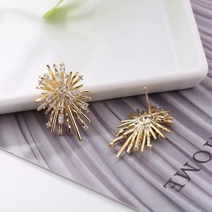 Detail of starburst stud earrings with gold plating and cubic zirconia on a ceramic tray