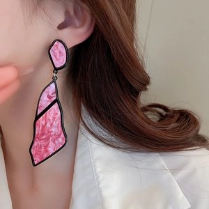 Close-up of oversized pink marble acrylic geometric drop earring with black border trim