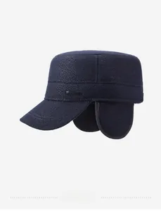 Detail view of navy wool flat cap with side metal fashion badge and ear protectors