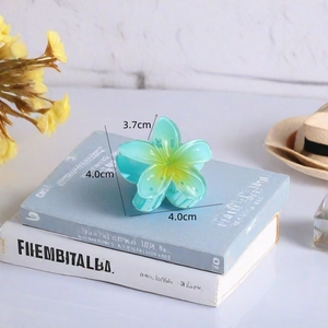 Detail view of a 4cm gradient flower hair claw clip on books with dimensional markers