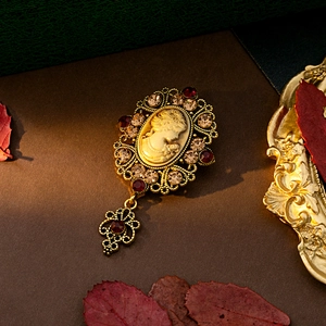 Detailed macro view of vintage cameo brooch with red rubies and intricate gold filigree