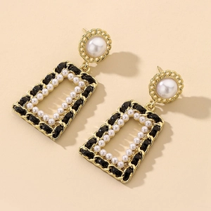 Detailed macro view of vintage geometric pearl earrings with gold and black woven textures