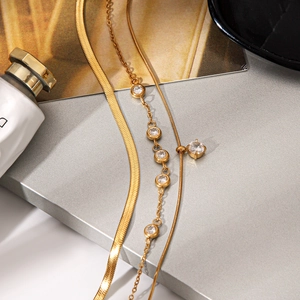 Layered gold titanium steel necklaces set with zircon pendant on metallic background