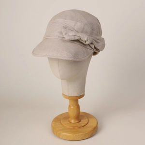 Elegant khaki cotton linen bucket hat with a side bow on a wooden display stand