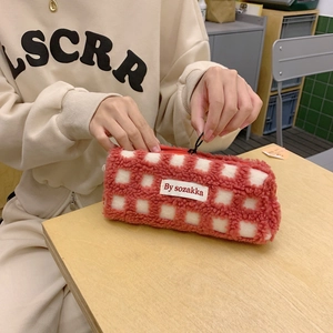 Macro shot of a red and white checkered waffle fleece pouch being opened on a wooden desk