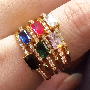 Macro shot of six gold rings set with colorful rectangular gemstones and small diamonds