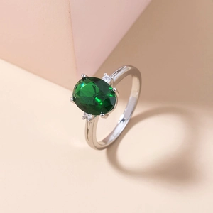 Close-up of a silver ring featuring a green oval gemstone with side diamond accents