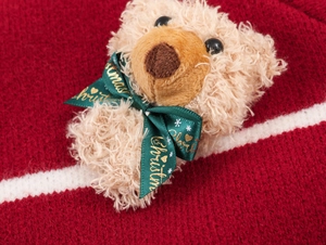 Détail de maille de Noël rouge avec tête d'ours en peluche et ruban vert festif