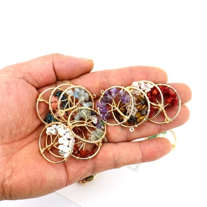Handheld view of various colorful tree of life pendants with natural crystal stones