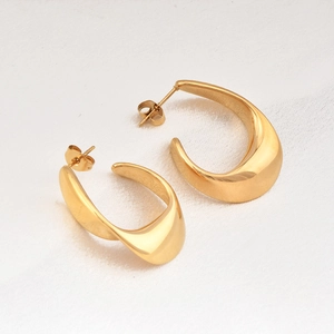 Polished gold stainless steel C-shaped stud earrings on white silk background