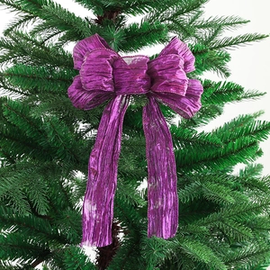 Sparkling purple Christmas bow ornament with metallic texture on a green pine tree