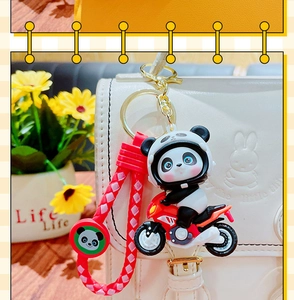 Close-up of a panda doll on a red motorcycle keychain with a woven strap on a bag