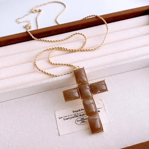 Detail of cross pendant necklace with brown resin stones and golden twist chain