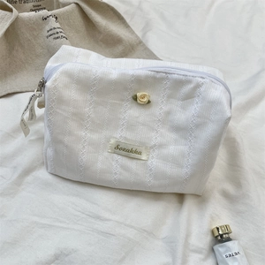 Detail of white lace makeup bag with floral embroidery and branded Sozakka label