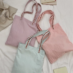 Detailed close-up of colorful canvas tote bags with red floral embroidery on straps