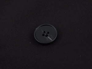 Macro view of black four-hole buttons on double-breasted suit jacket fabric