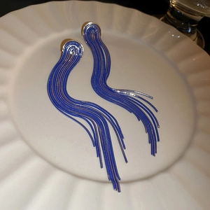 Detail of blue tassel earrings with long chain fringe on white ceramic tray