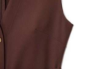 Detailed macro view of dark coffee crepe midi dress fabric with fine seams and gold button