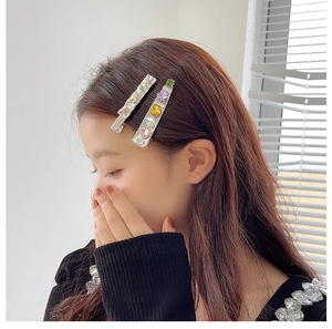 Close-up of model wearing silver metal hair clips with colorful zircons and heart charms