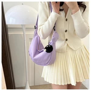 Detail of purple canvas half-moon crossbody bag with coin purse and plush charm