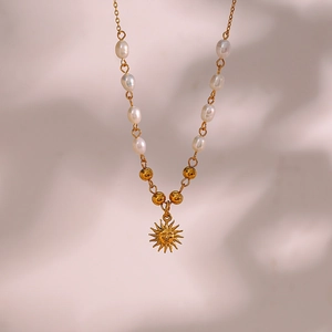 Close-up of golden sun face pendant with elegant white pearl chain on soft background