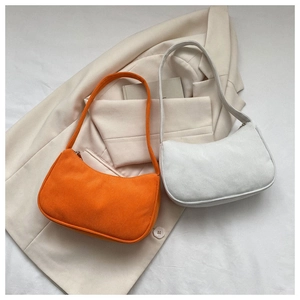 Detailed view of orange and beige corduroy baguette shoulder bags on professional attire