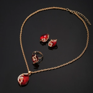 Close-up of golden necklace and earring set with red teardrop stones and white diamonds