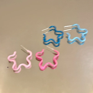 Détail de boucles d'oreilles étoile ondulées en émail rose, bleu foncé et bleu ciel brillant