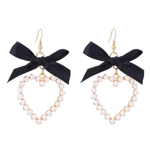 Détail de boucles d'oreilles nœud noir avec pendentif cœur en perles et crochets dorés