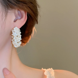 Detail of floral cluster drop earrings featuring white petals and metallic bead centers