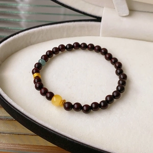 Detailed view of dark brown wood beads with yellow amber and gold spacer in a jewelry box
