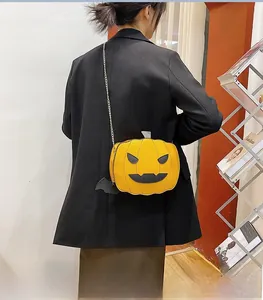 Detail of yellow pumpkin crossbody bag featuring black bat wings and gold chain strap