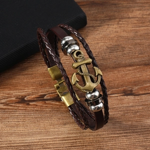 Detail of vintage multilayer braided brown leather bracelet with bronze anchor charm