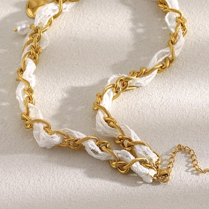 Detail of 18K gold-plated chain woven with white lace featuring a lobster clasp closure
