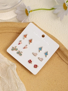 Close-up of 6 pairs of enamel earrings with animal and ballet motifs on a weekly card