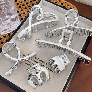 Detail of five-piece silver metal hair claw set featuring heart and geometric designs