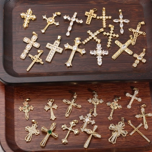 Pendenti croce punk vintage con zircone in oro e argento su un vassoio di legno