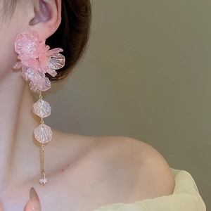 Close-up of pink acrylic flower tassel earrings with golden chain on female model