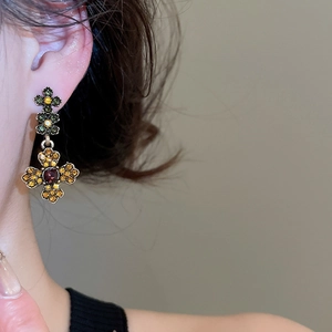 Detailed view of vintage cross-flower earrings with colorful rhinestones on a model
