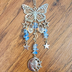 Close-up of silver butterfly suncatcher with blue crystals and celestial moon pendants