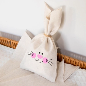 Detail view of bunny ear linen gift bags in a woven basket for Easter party decorations